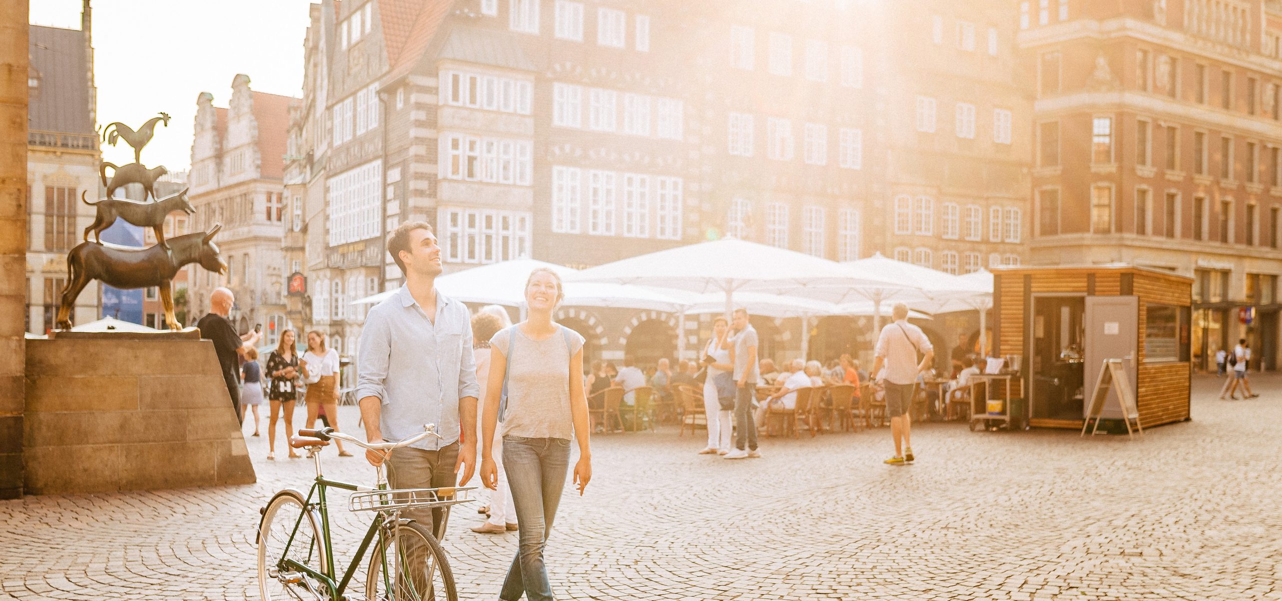 Zwei Personen stehen auf dem Bremer Marktplatz bei Sonnenschein.