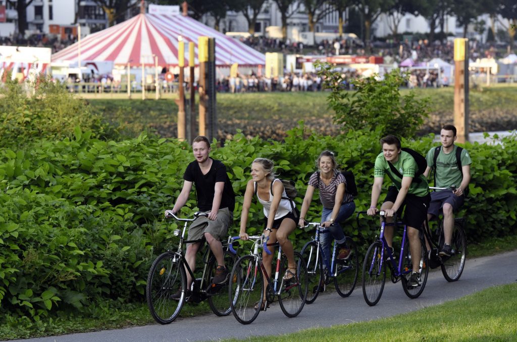 Fünf Personen fahren auf dem Fahrrad. Im Hintergrund findet die Breminale statt.
